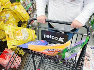 a person pushing a petco shopping cart with dog treats in top part of cart