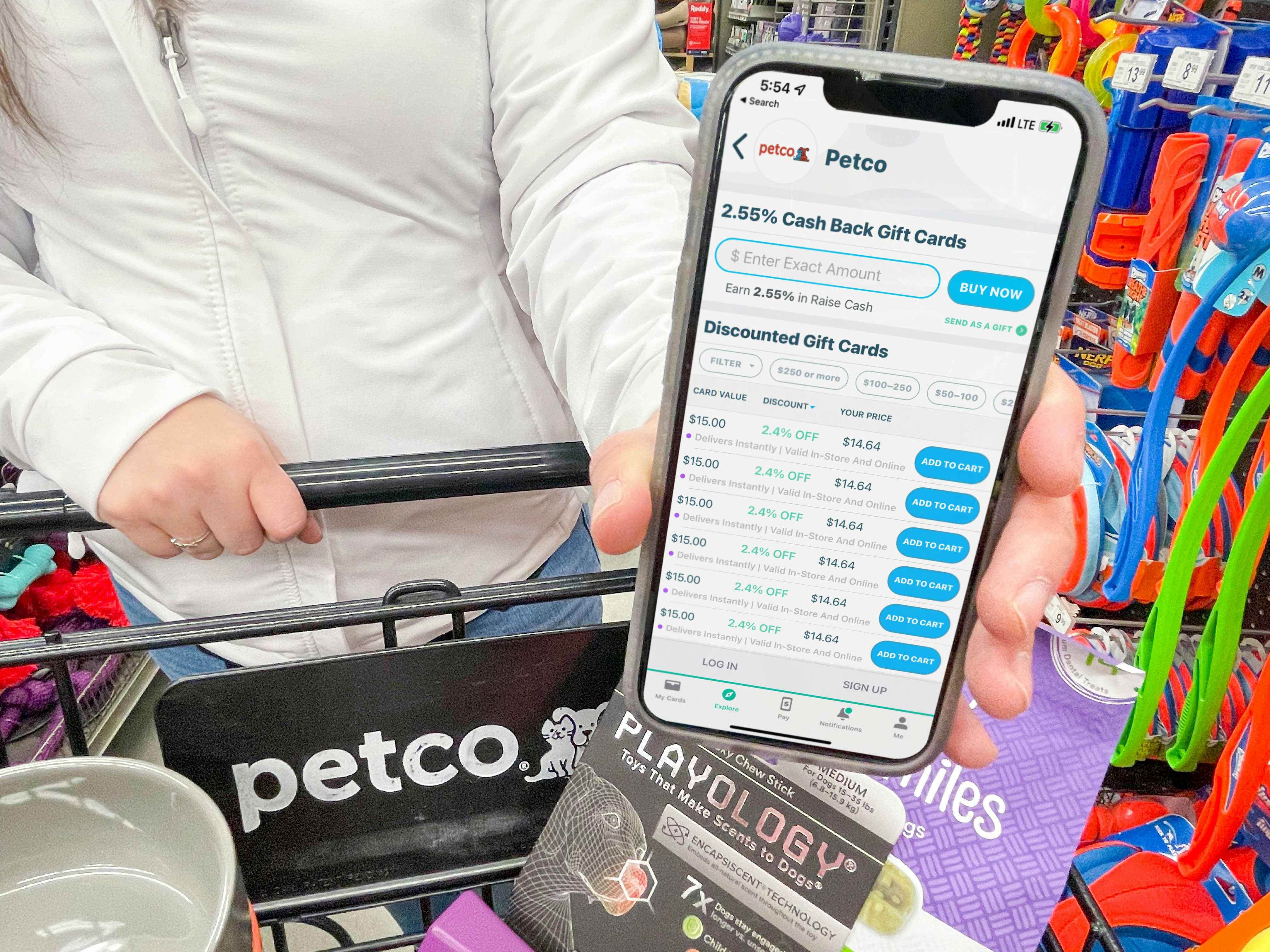 a person holding out a cellphone with raise app and petco gift cards on screen in store by cart