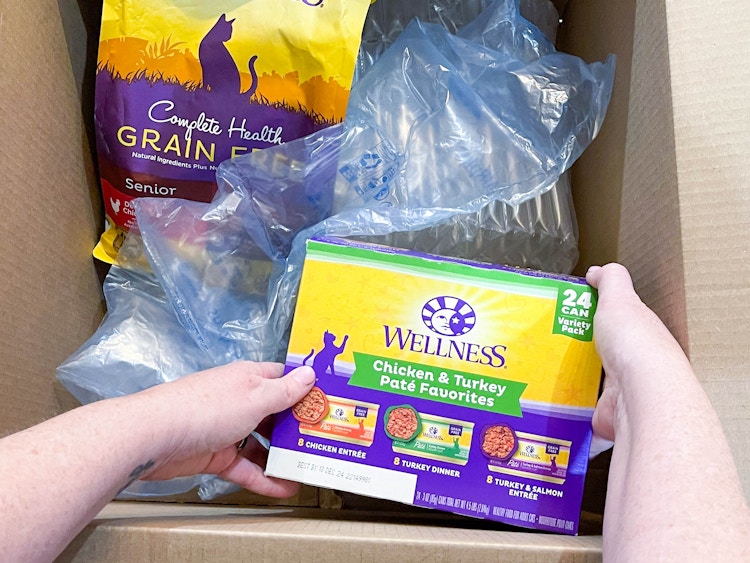 a person pulling cat food out of a box 