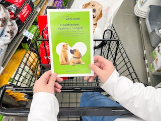 a person at at shopping cart looking at a brochure in store for petco vital care