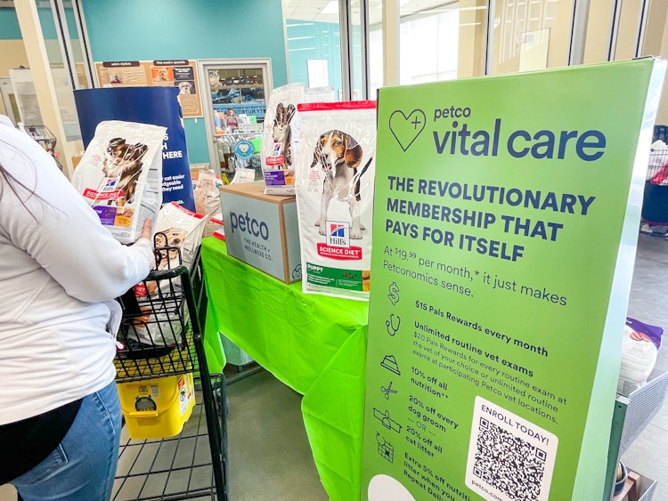 a person pushing a shopping cart in petco store near large vital care sign 