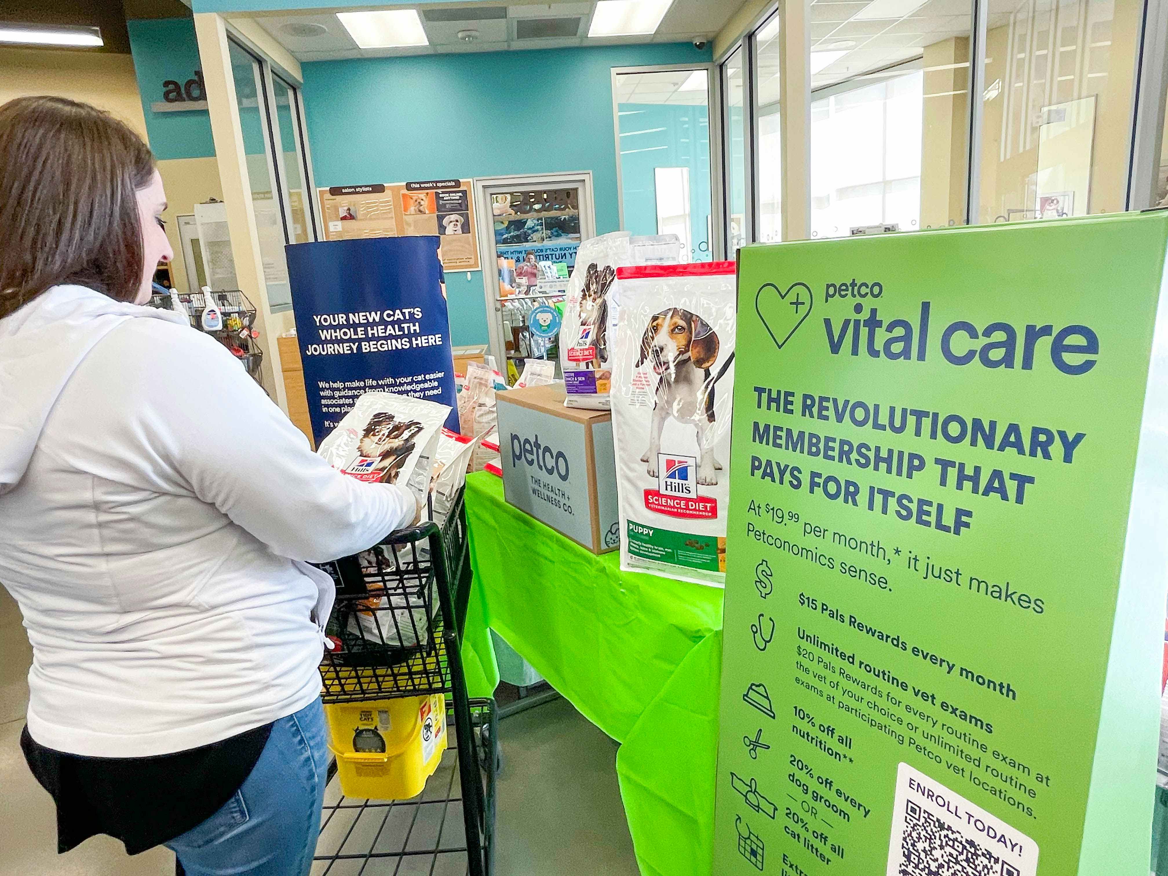 a person pushing a shopping cart in petco store near large vital care sign