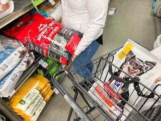 a person loading up a large bag of worlds best cat litter into petco cart