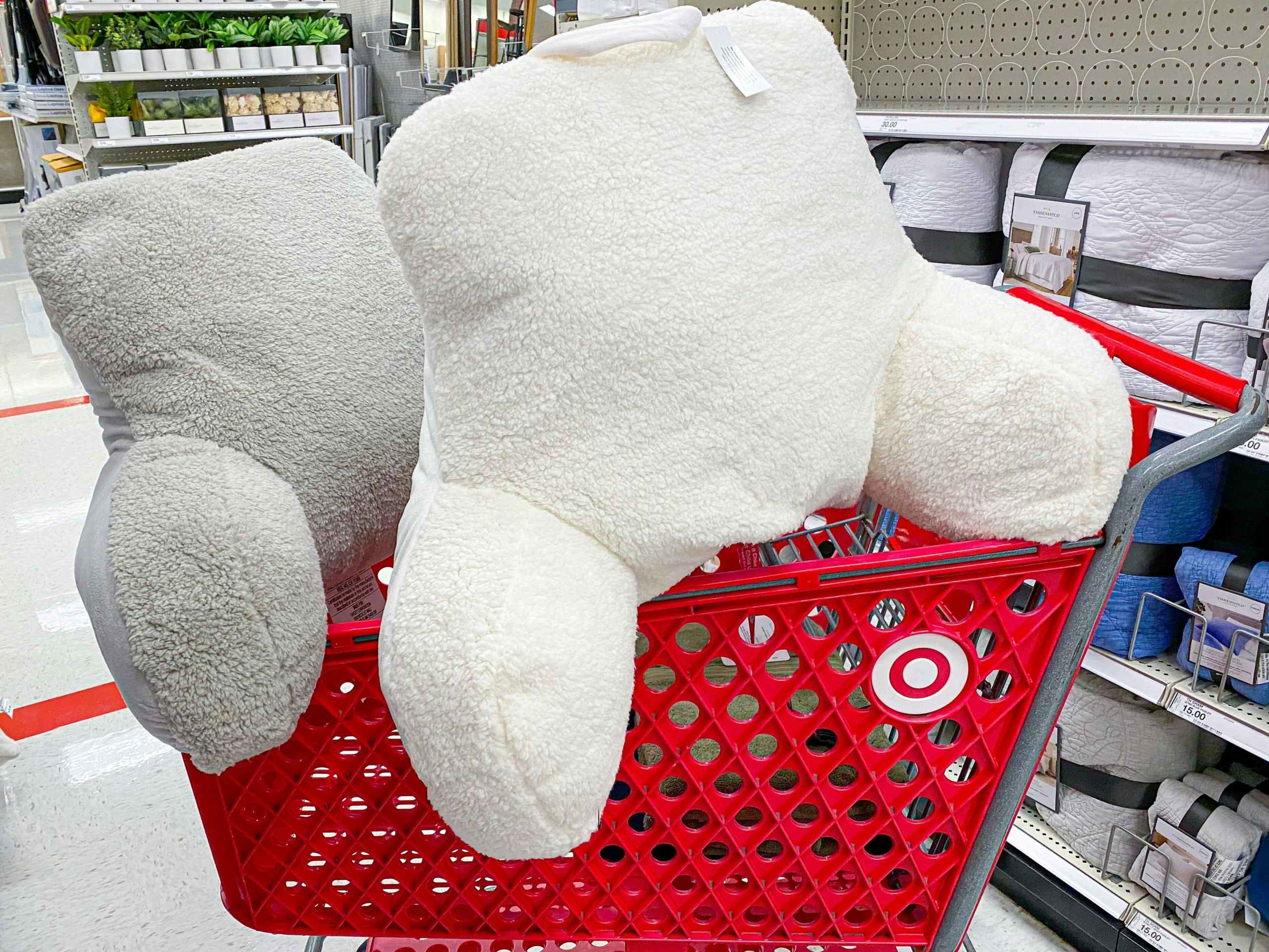 Two Room Essentials sherpa bed rest pillows on top of a Target shopping cart in an aisle at Target.