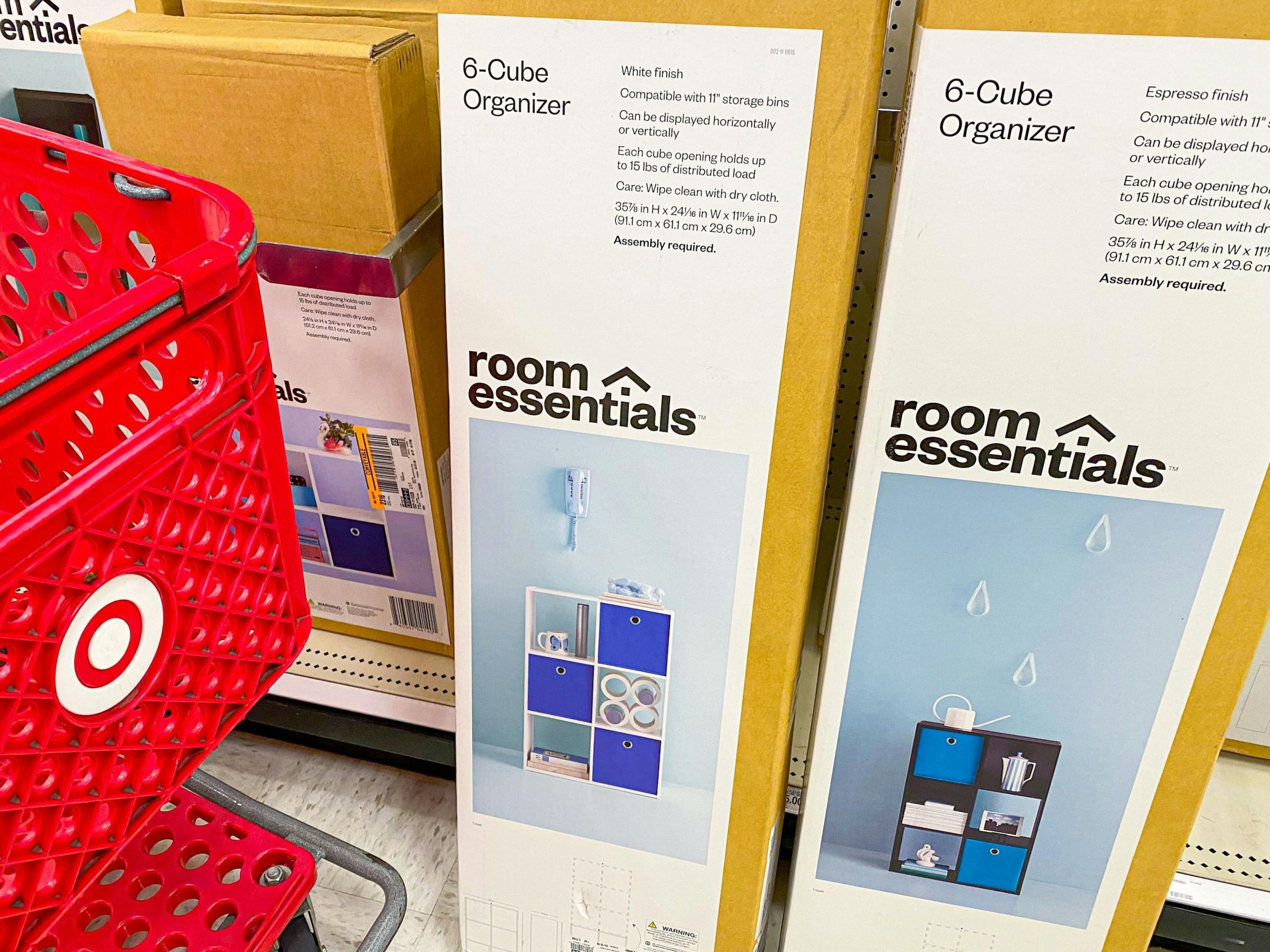 Two boxes for Room Essentials 6-Cube Organizers on the floor in front of the shelf, next to a Target shopping cart.