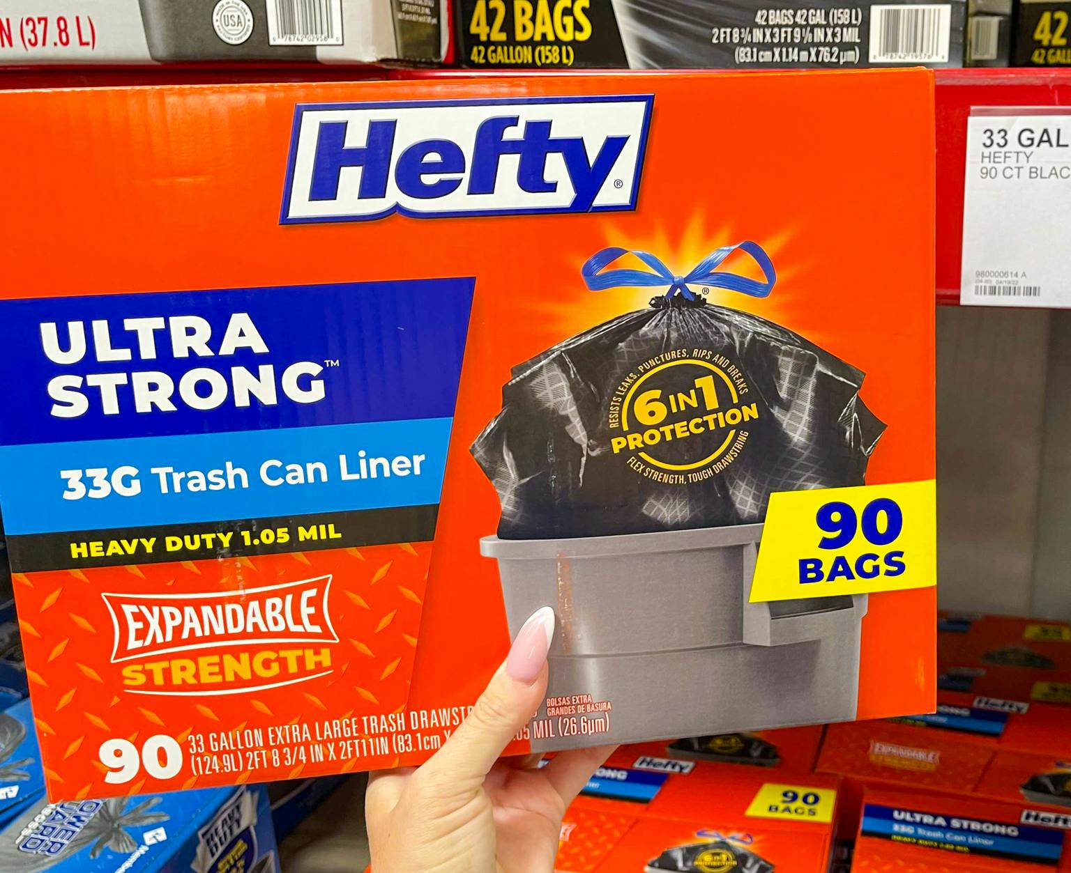 hand holding a box of hefty trash bags 90 ct