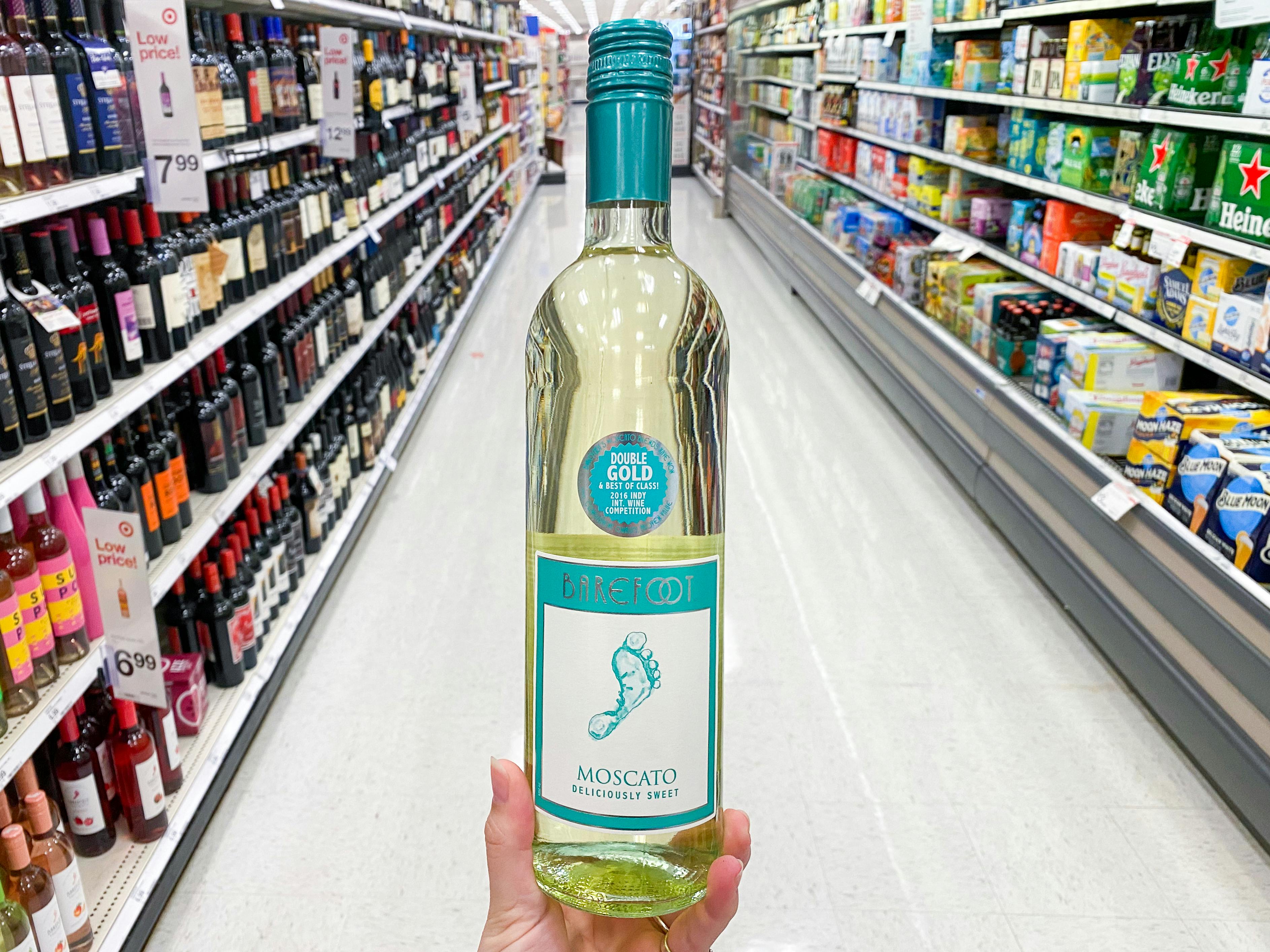 A person's hand holding up a bottle of Barefoot Moscato wine in the Wine and Beer aisle at Target.