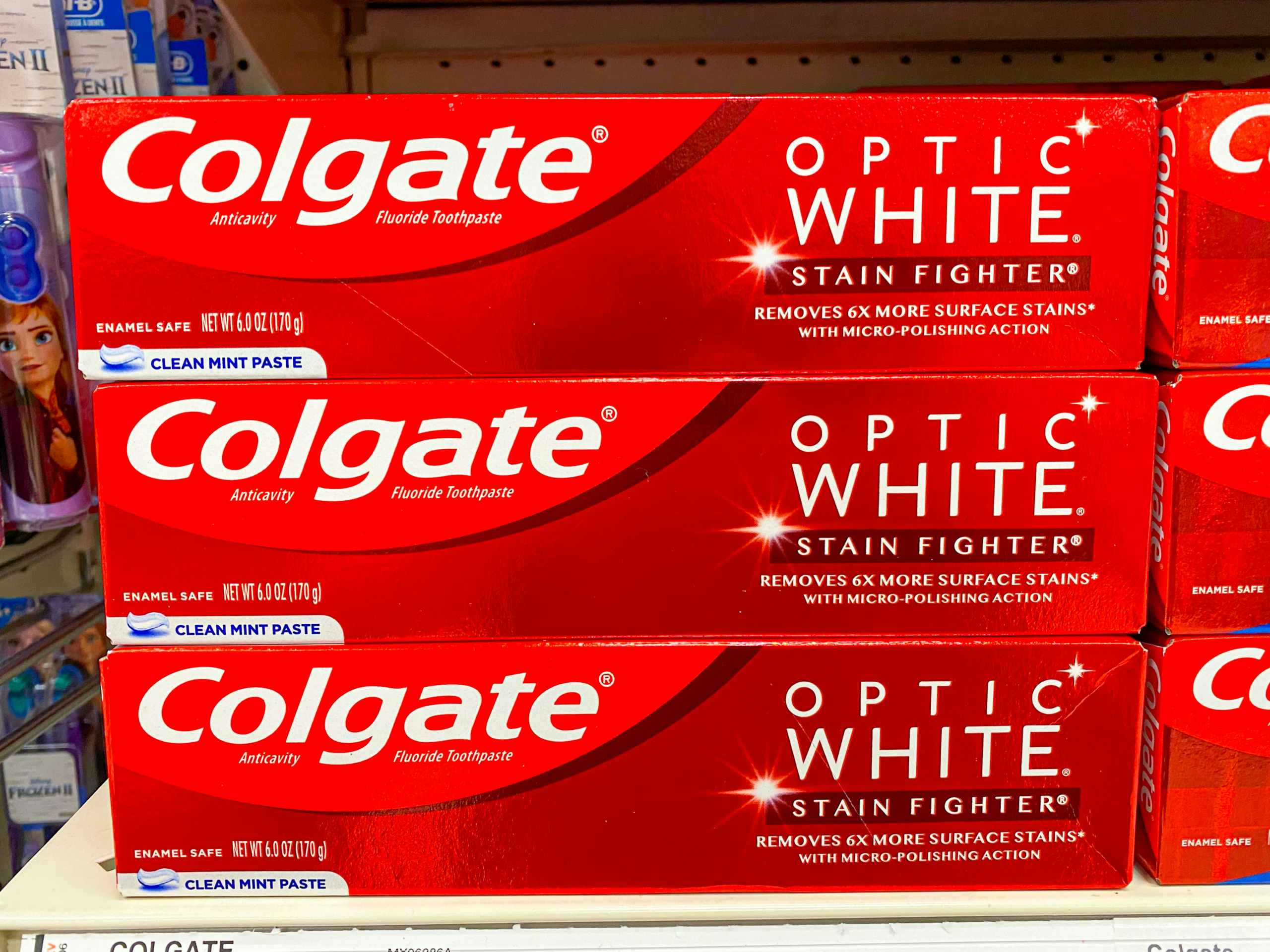 Three boxes of Colgate Optic White Stain Fighter toothpaste stacked on a shelf at Target.