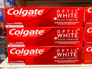 Three boxes of Colgate Optic White Stain Fighter toothpaste stacked on a shelf at Target.