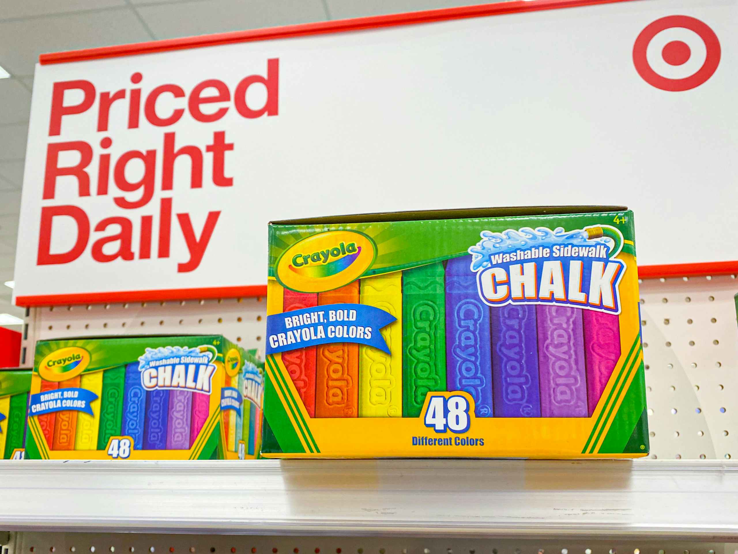 Boxes of 48 count Crayola Washable Sidewalk Chalk stocked on an endcap shelf at Target, in front of a sign that says, "Priced Right Daily