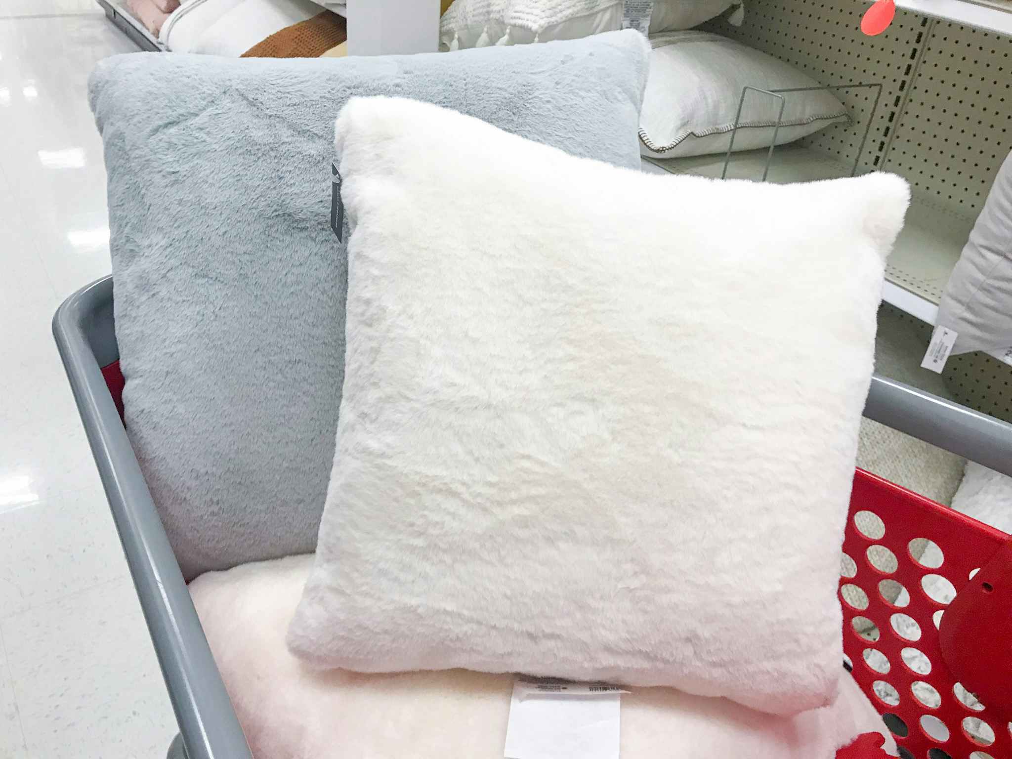 Three faux rabbit fur throw pillows in a Target shopping cart.