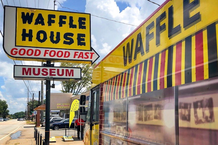 A sign for the Waffle House Museum outside of a Waffle House storefront.