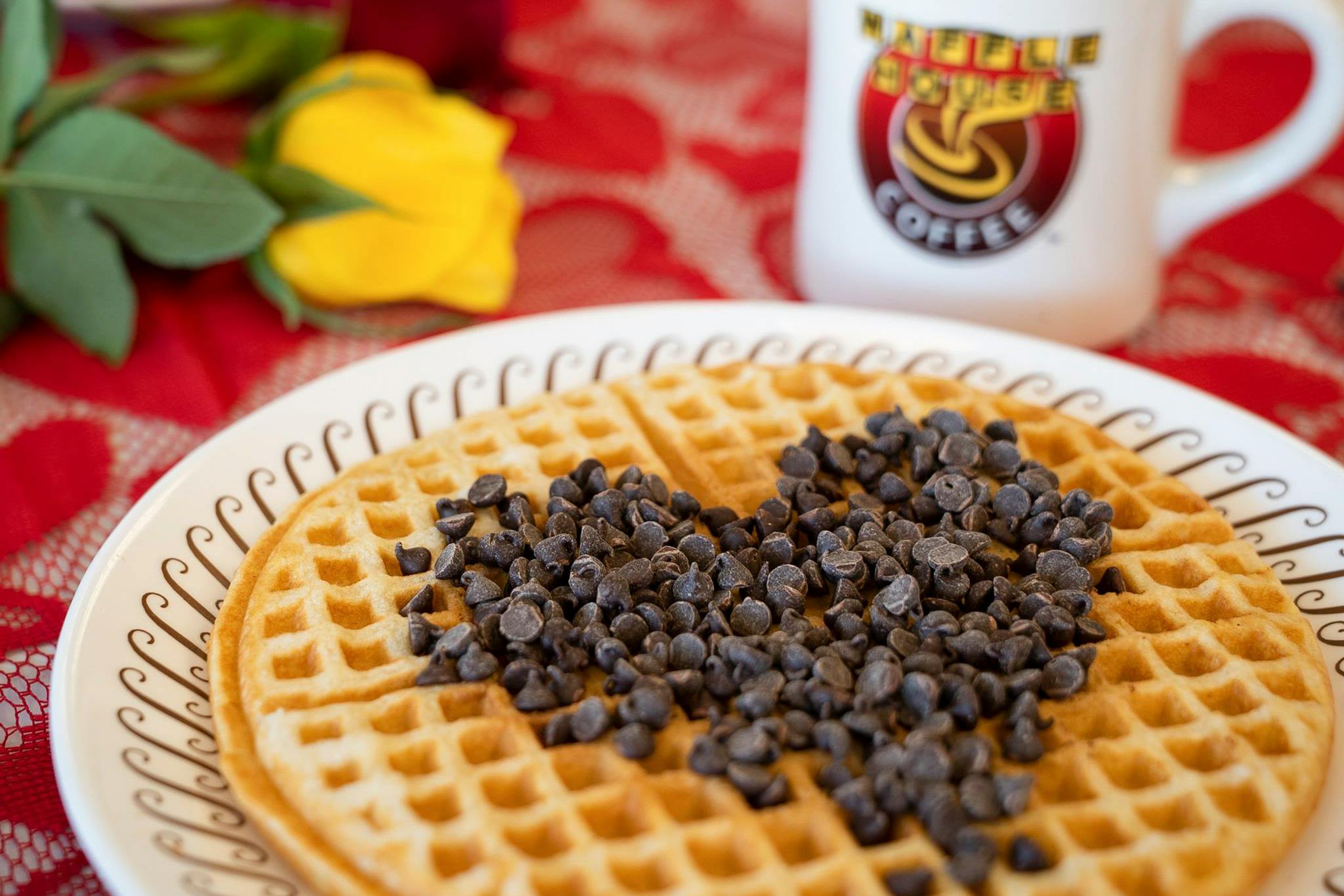 A Waffle House waffle with chocolate chips on top of it in the shape of a heart.