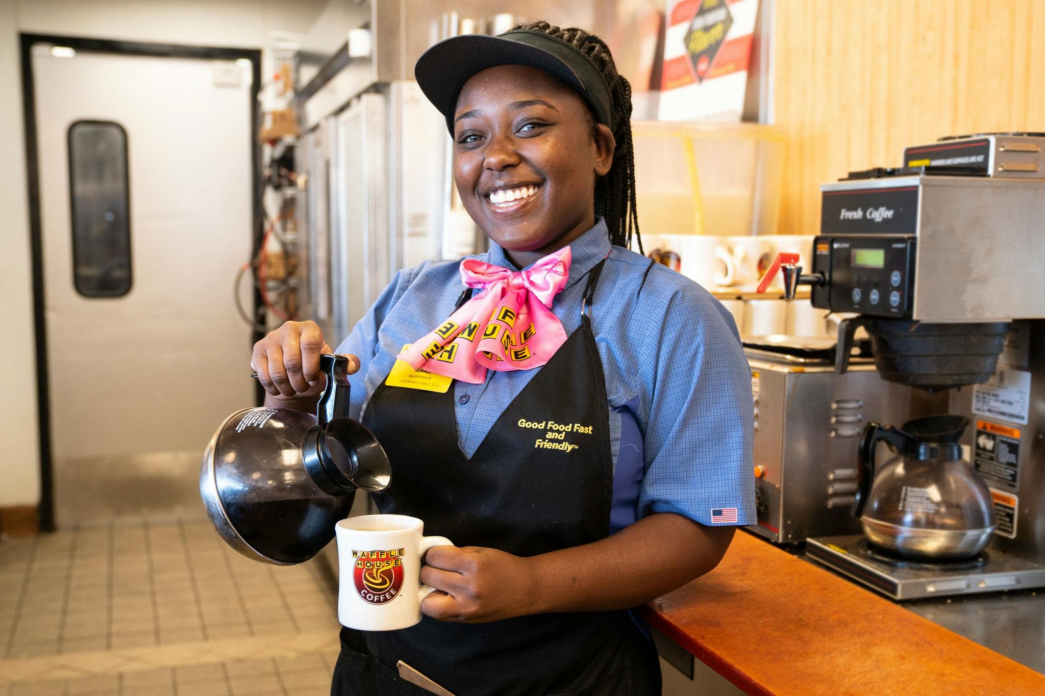 A Waffle House employee holding a coffee cup and coffee pot