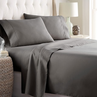 A bed with gray sheets.