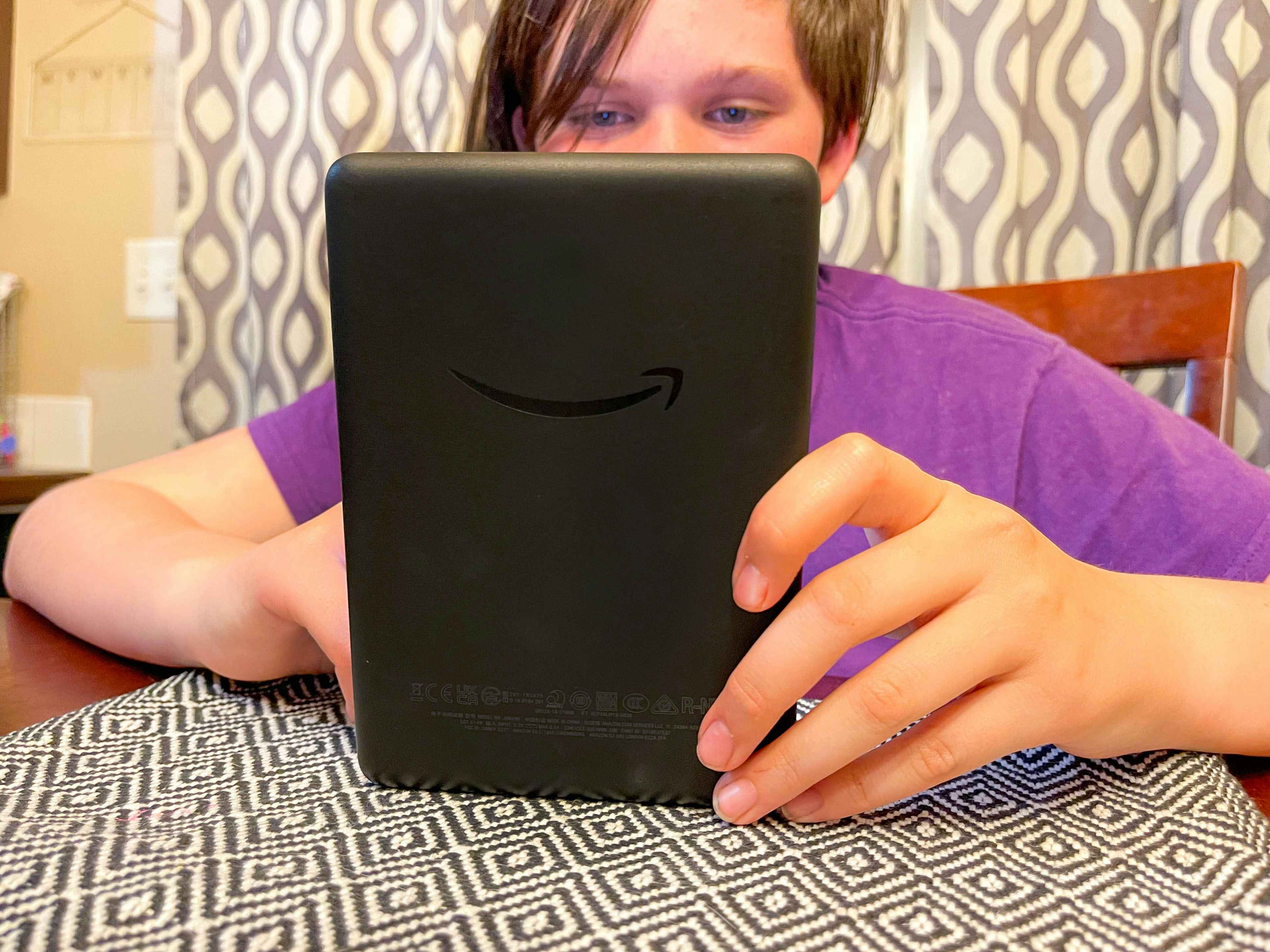 a teen reading on a kindle at the table