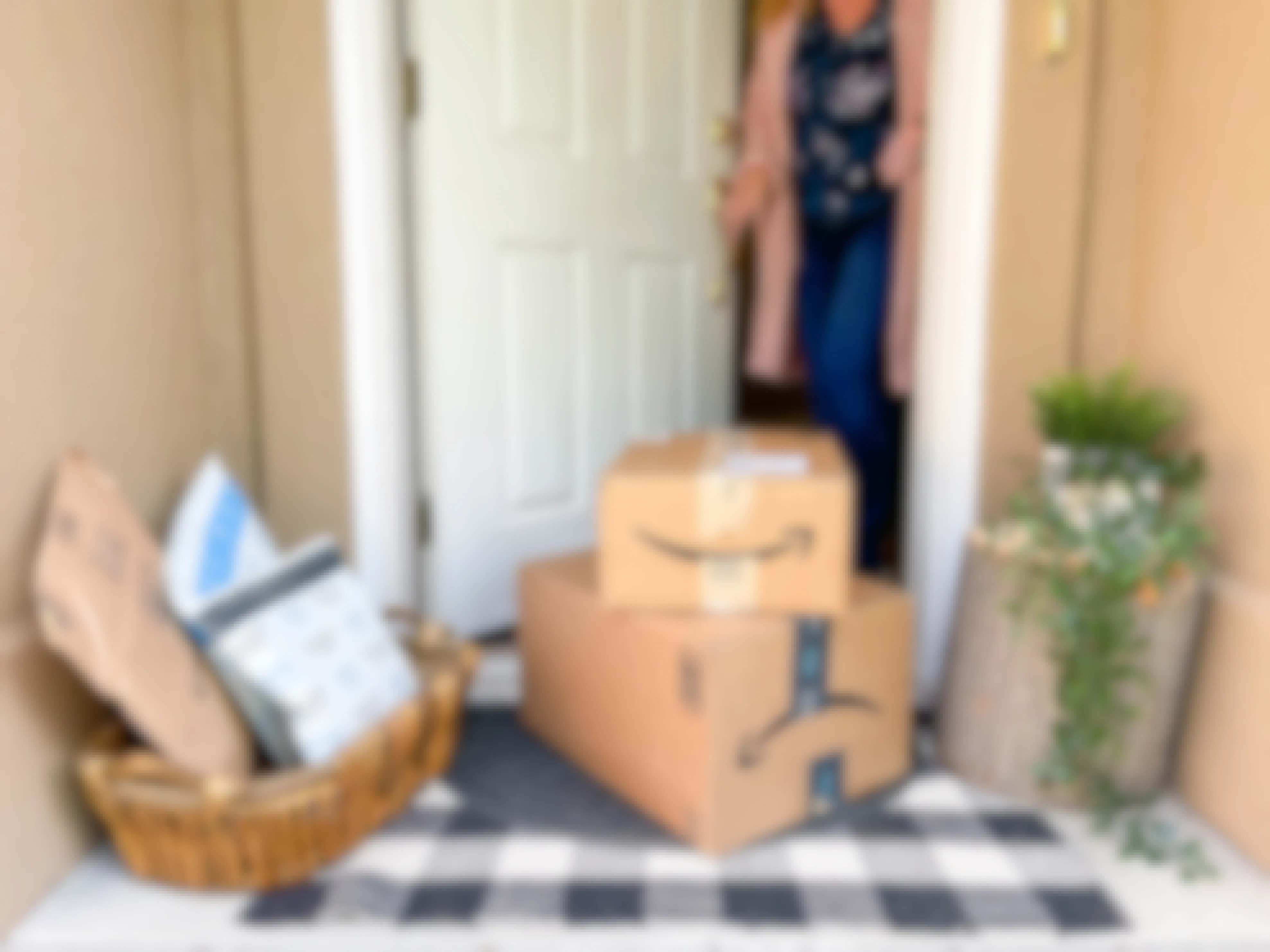 a person picking up amazon boxes next to a basket with packages on front porch