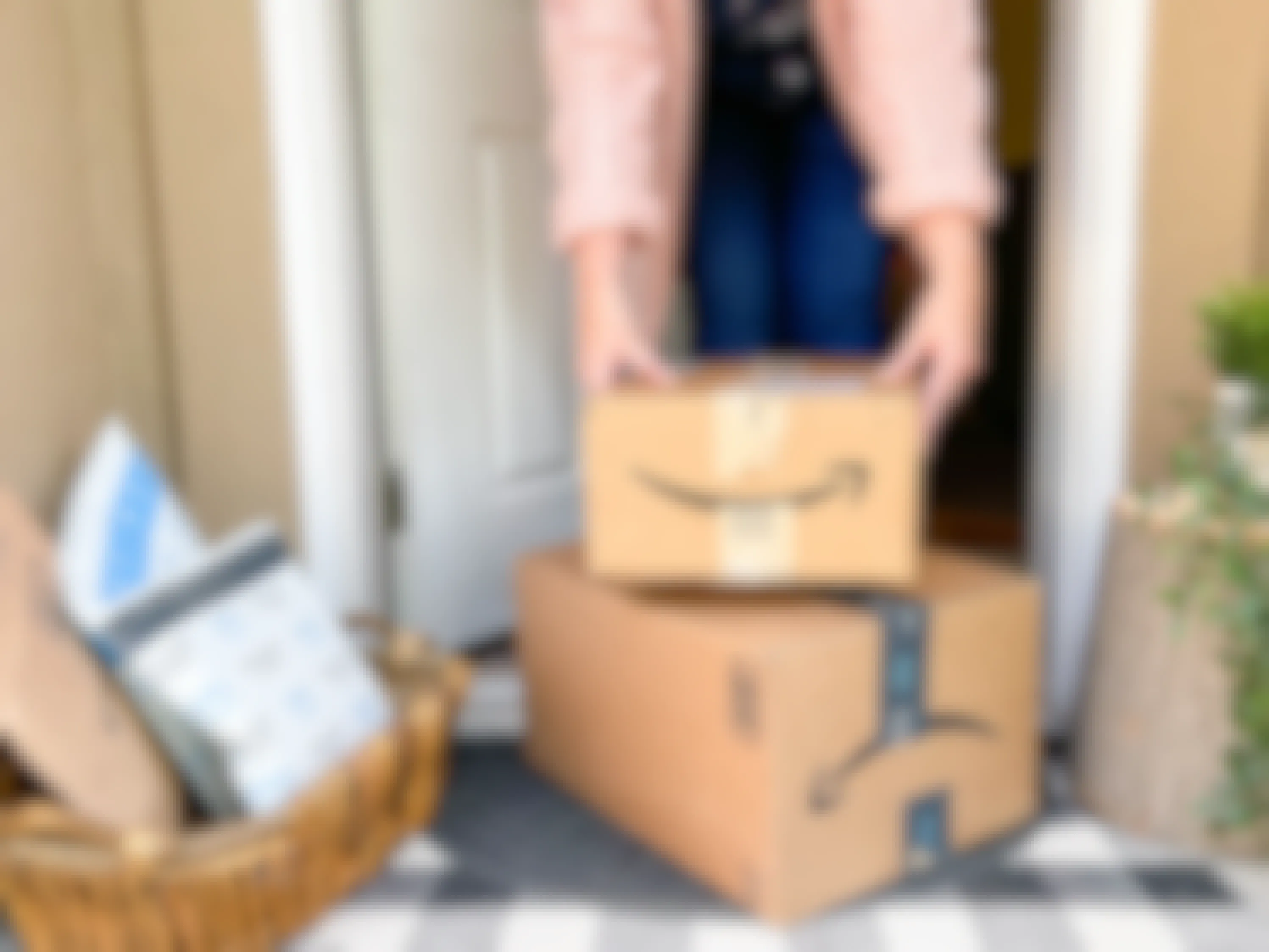 a person picking up amazon boxes next to a basket with packages on front porch