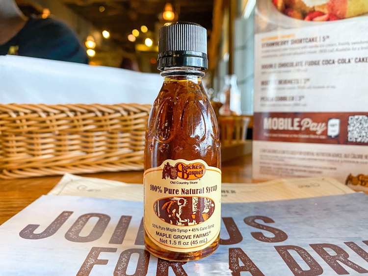 A small Cracker Barrel syrup bottle sitting on a table at Cracker Barrel.