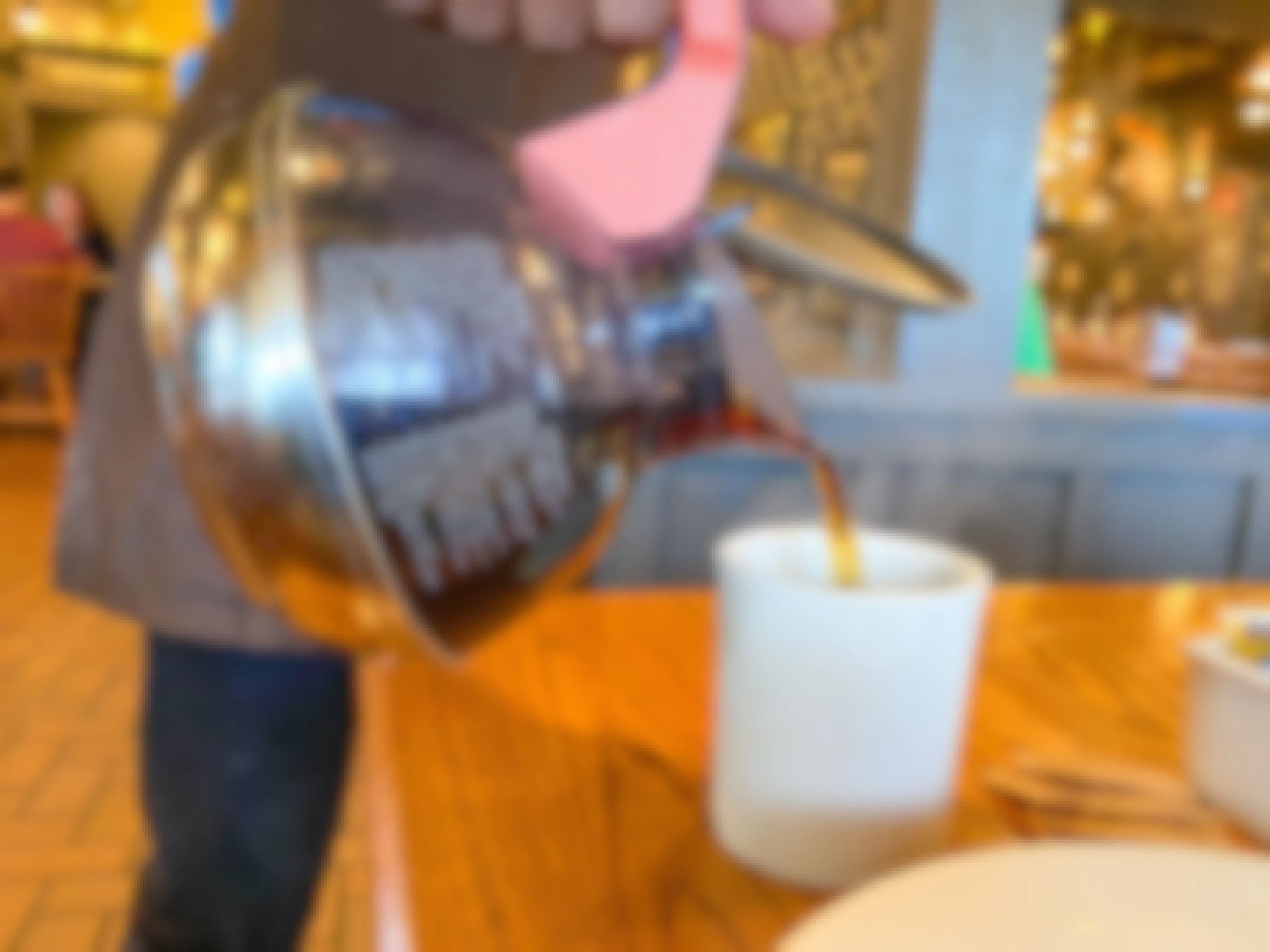 A Cracker Barrel server pouring coffee into a coffee mug at a table at Cracker Barrel.