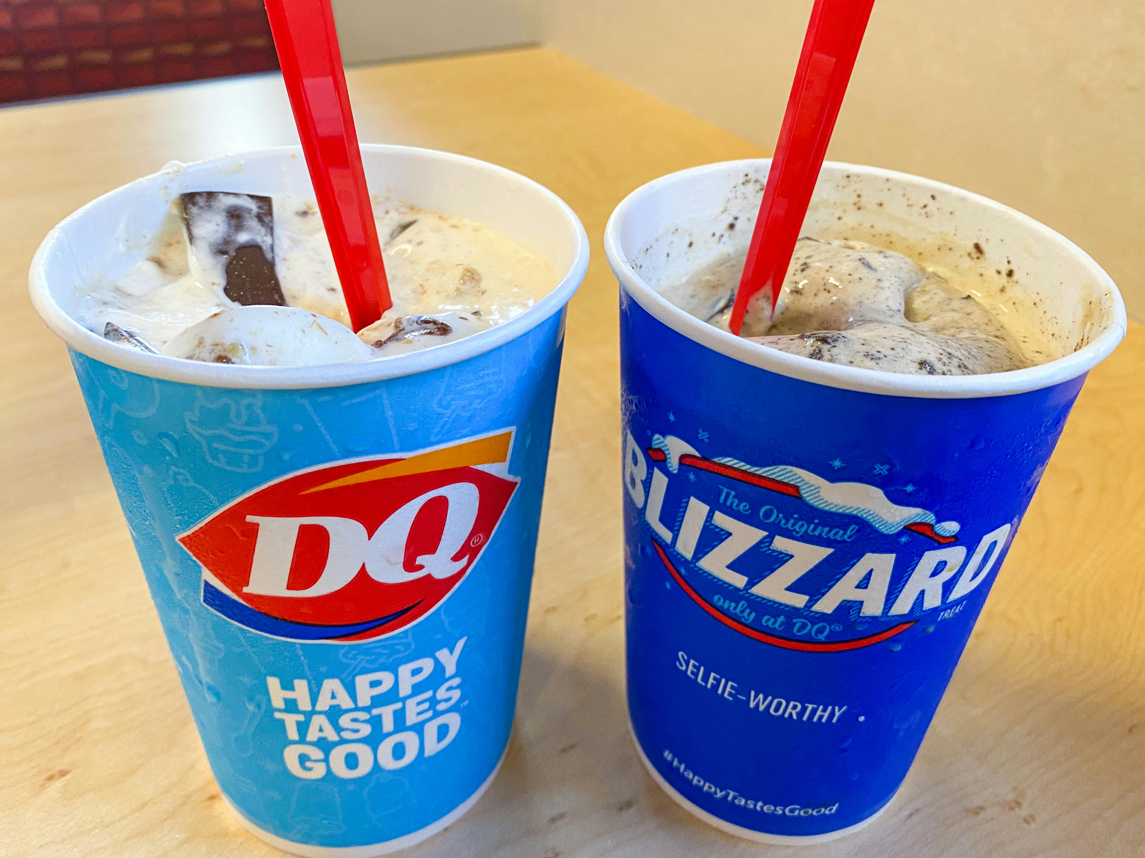 Two Blizzards from Dairy Queen sitting on a table inside the restaurant.