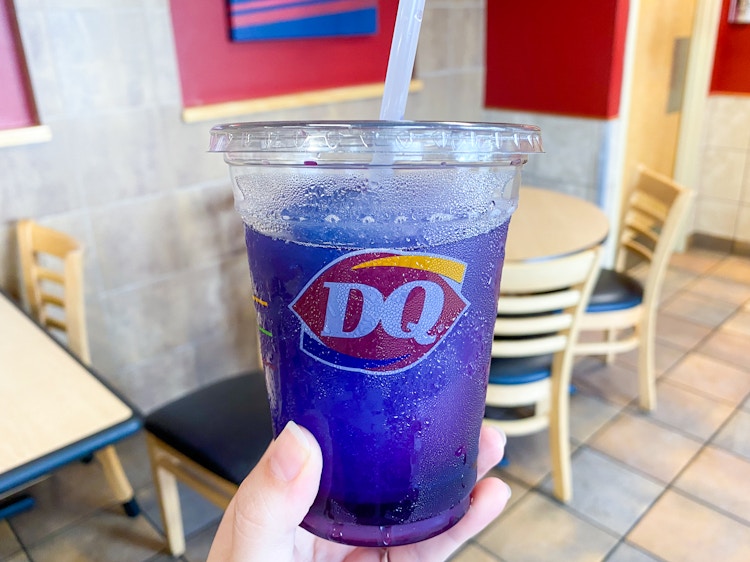 A person's hand holding up a Misty Slush drink inside Dairy Queen.