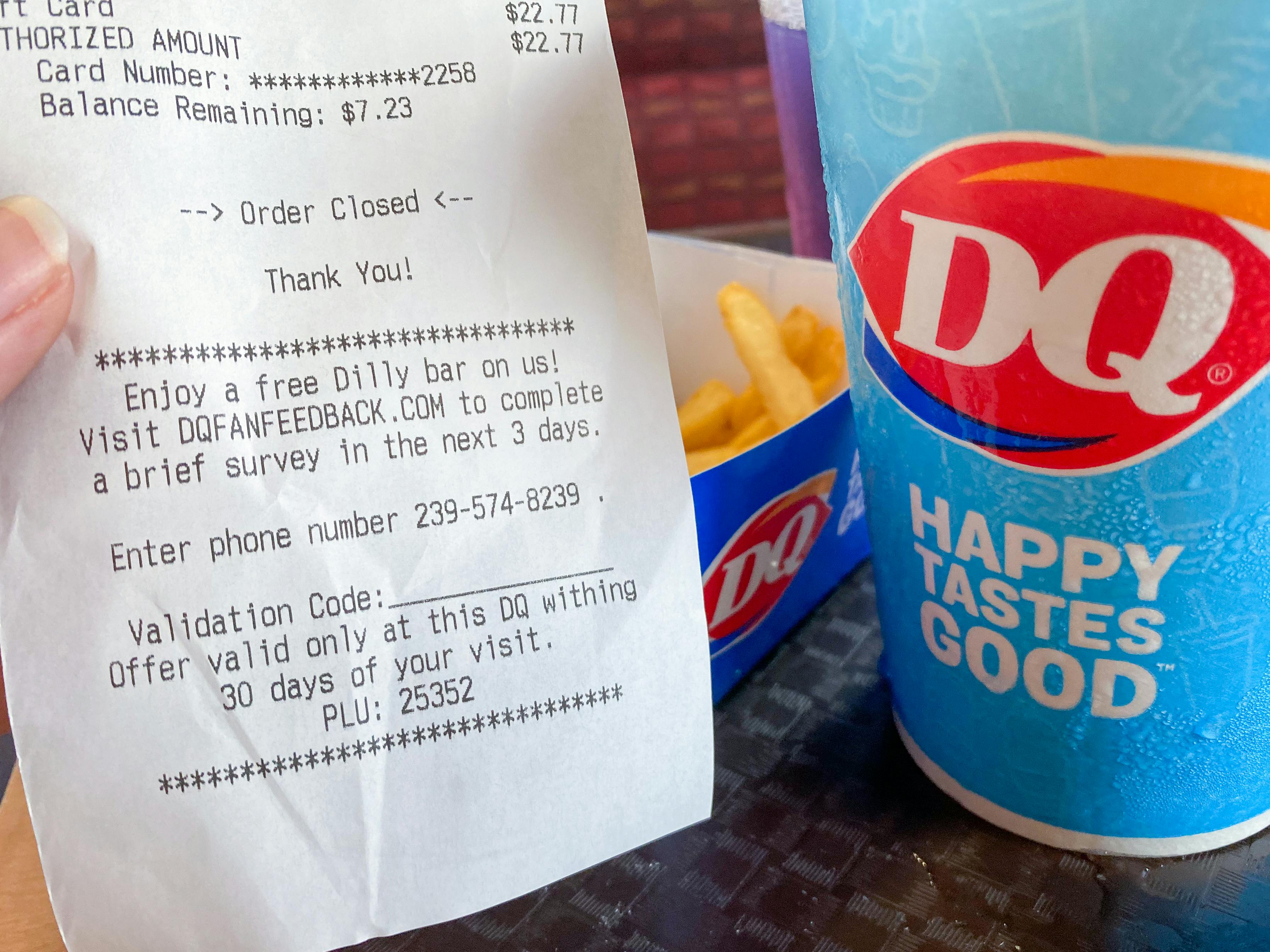 A close-up of a Dairy Queen receipt next to a Blizzard cup sitting on a table inside Dairy Queen.