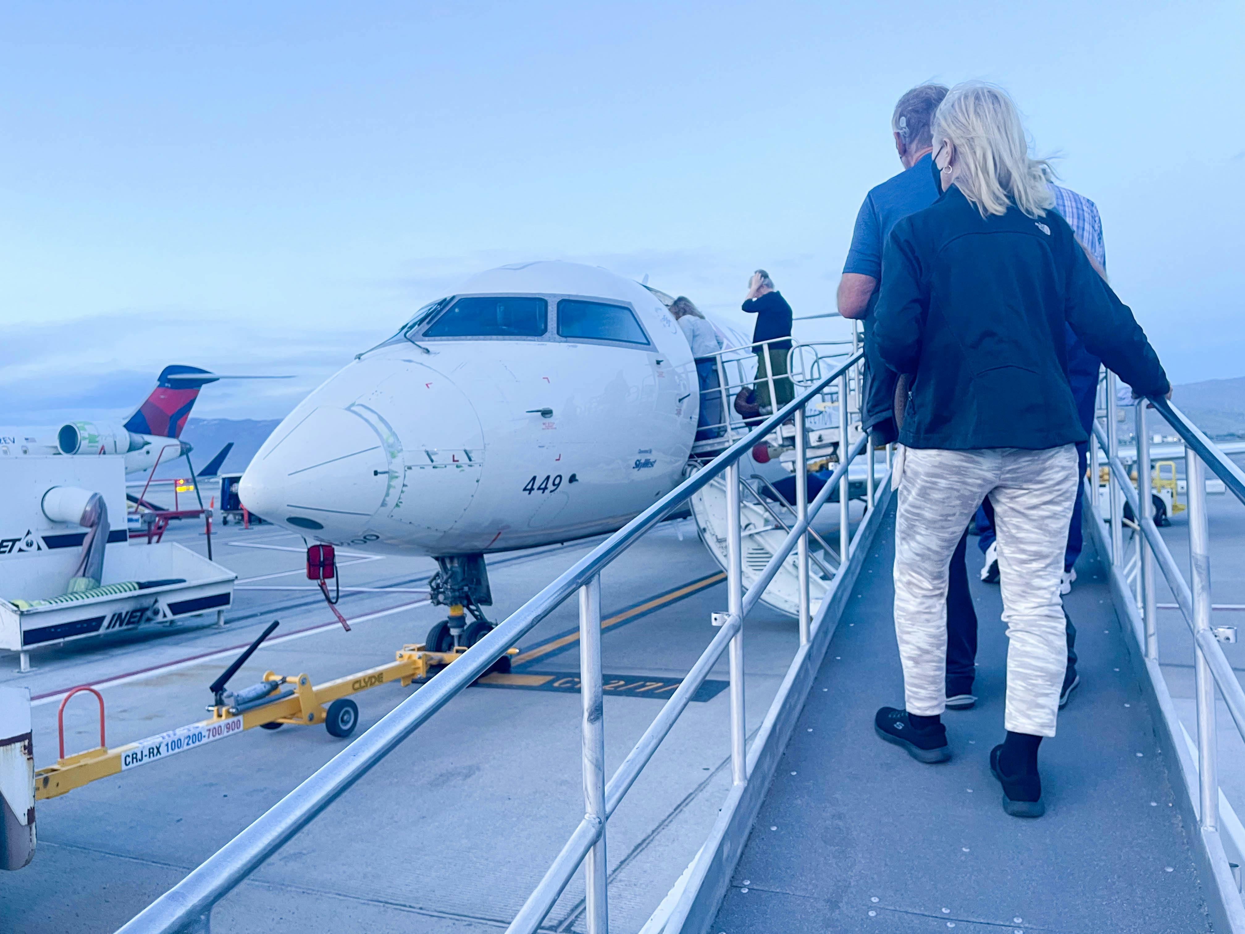 people walking on outside ramp onto a small plane