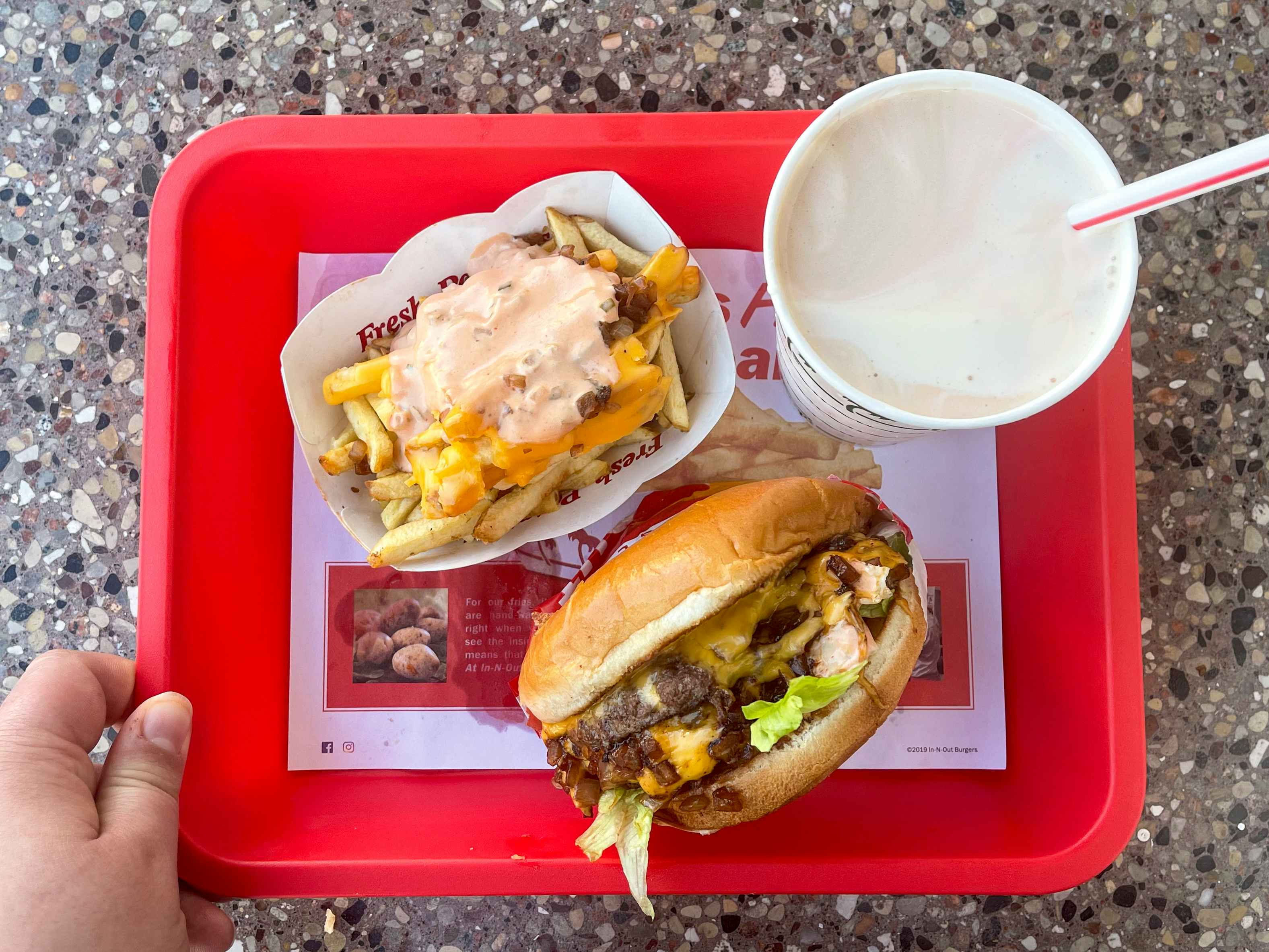 An In-N-Out burger, milkshake, and animal-style french fries on a red fast food tray.