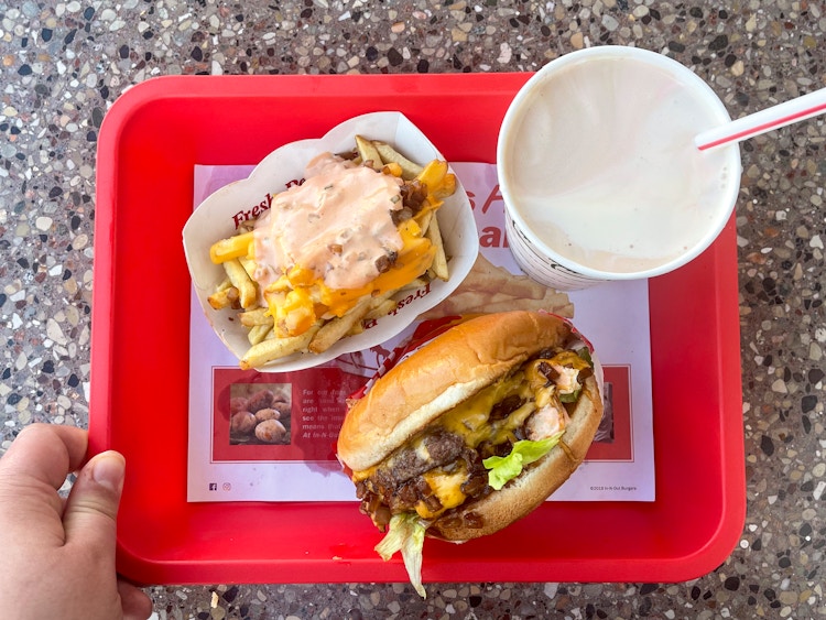 An In-N-Out burger, milkshake, and animal-style french fries on a red fast food tray.