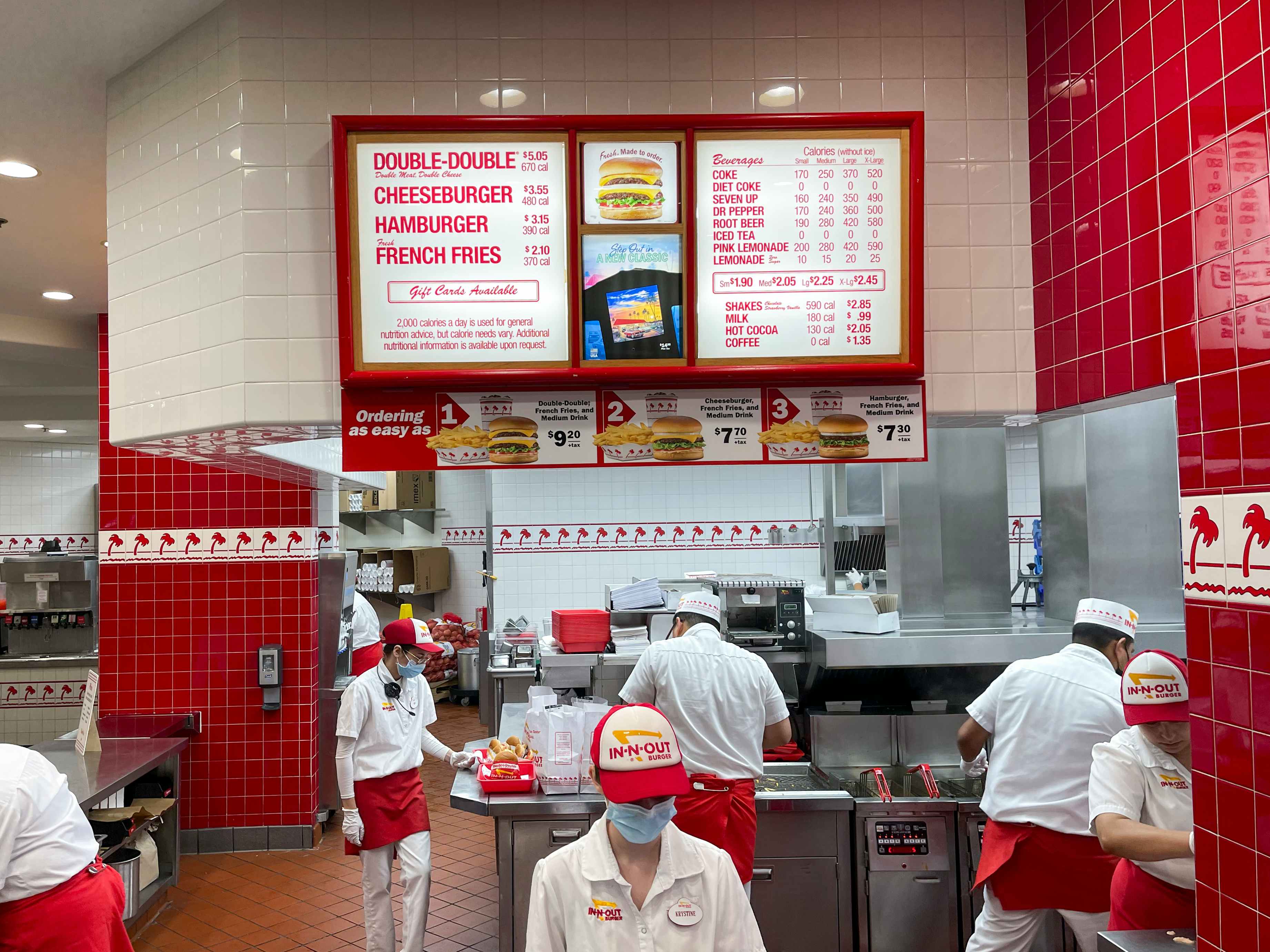 The ordering counter at In-N-Out burger with employees working in the kitchen.