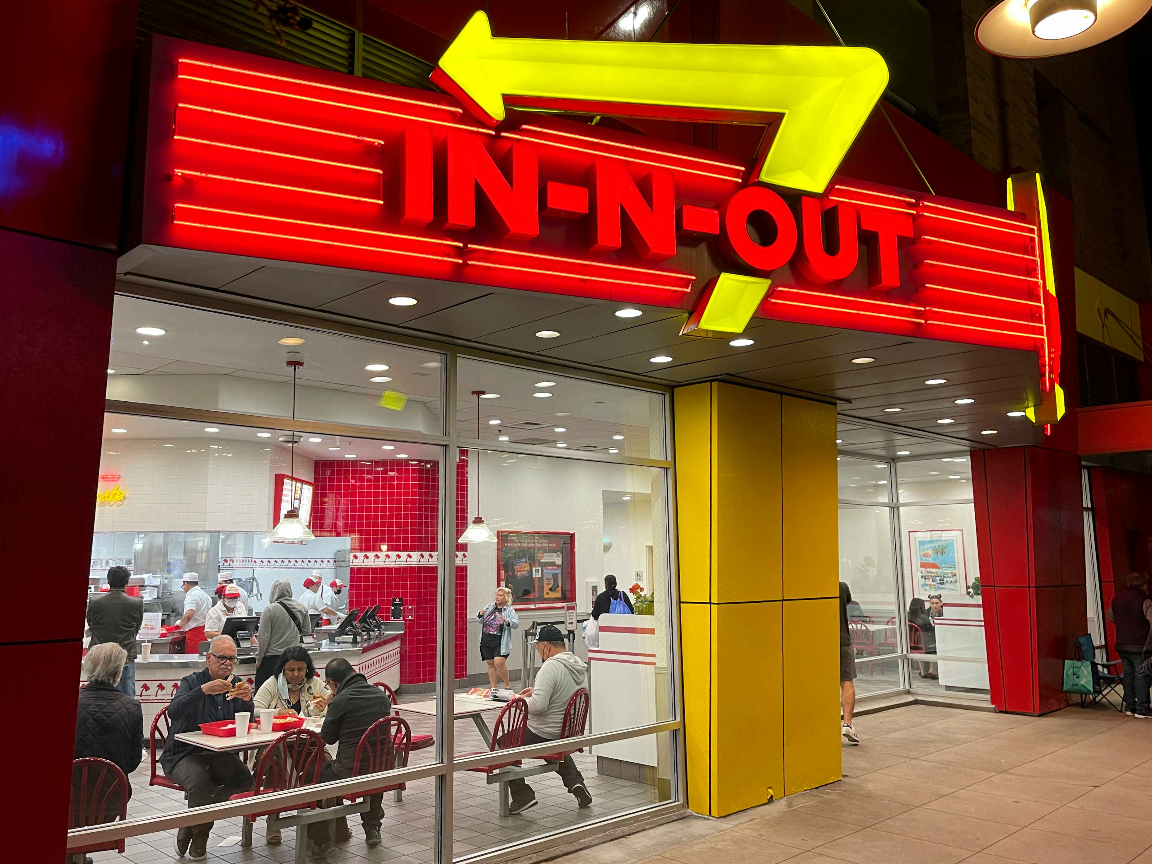 An In-N-Out restaurant storefront at night with the sign lit up.