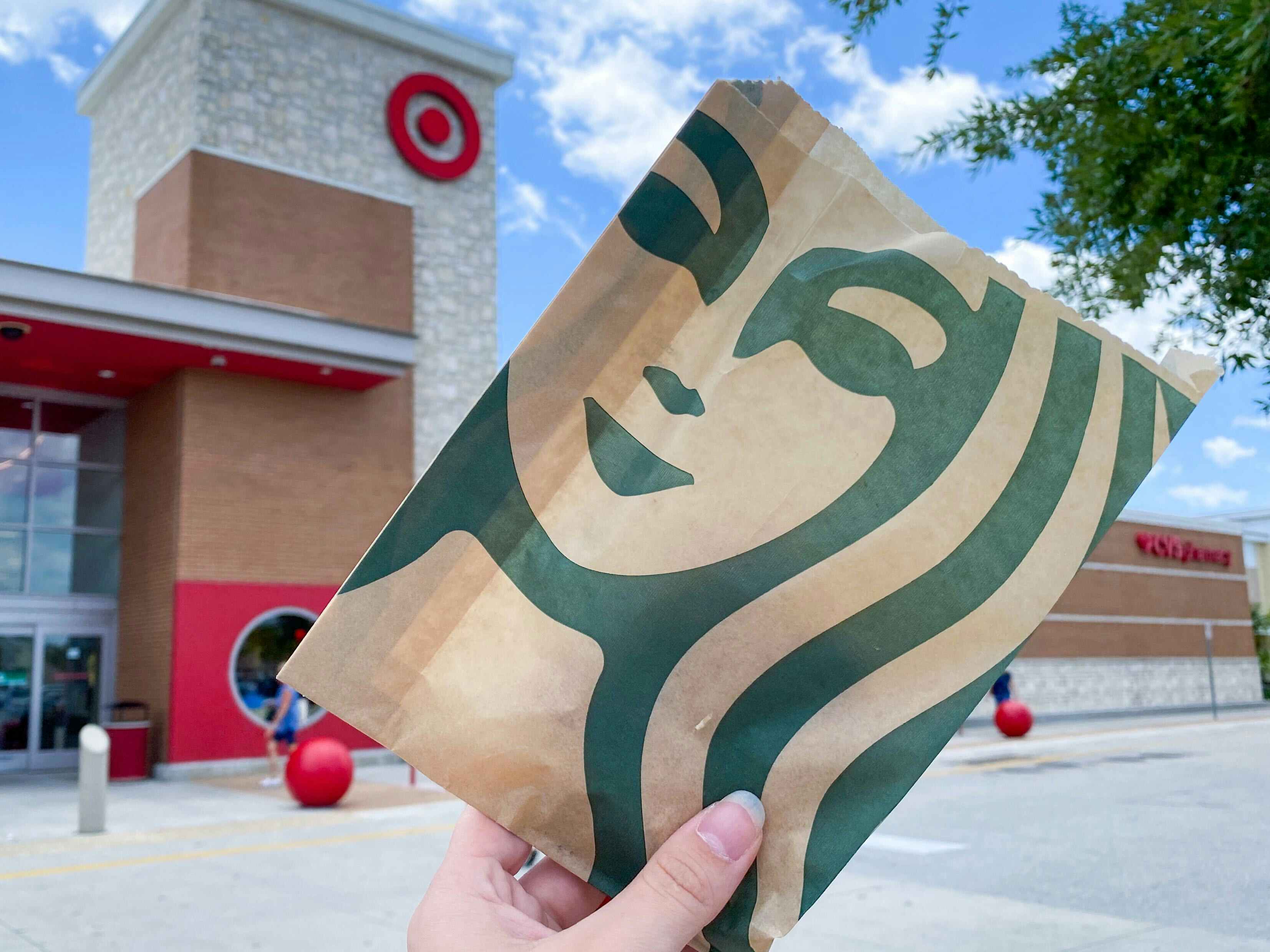 A person holding a Starbucks food bag outside of a Target store