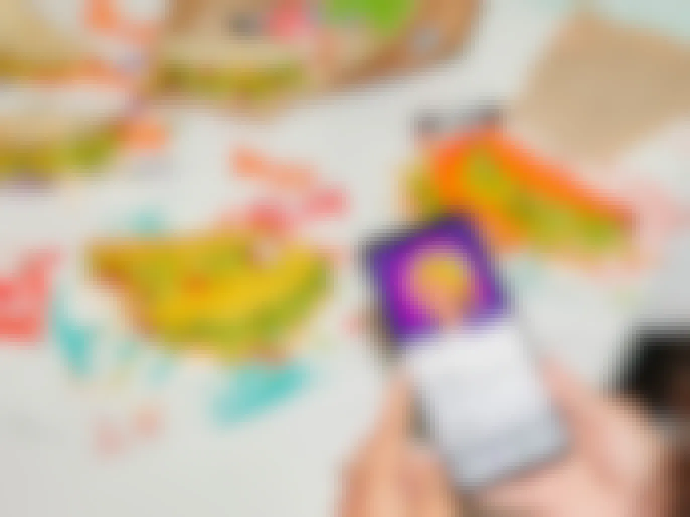 A person's hands holding their phone displaying the Taco Lovers Pass on the Taco Bell app in front of a table of unwrapped tacos.