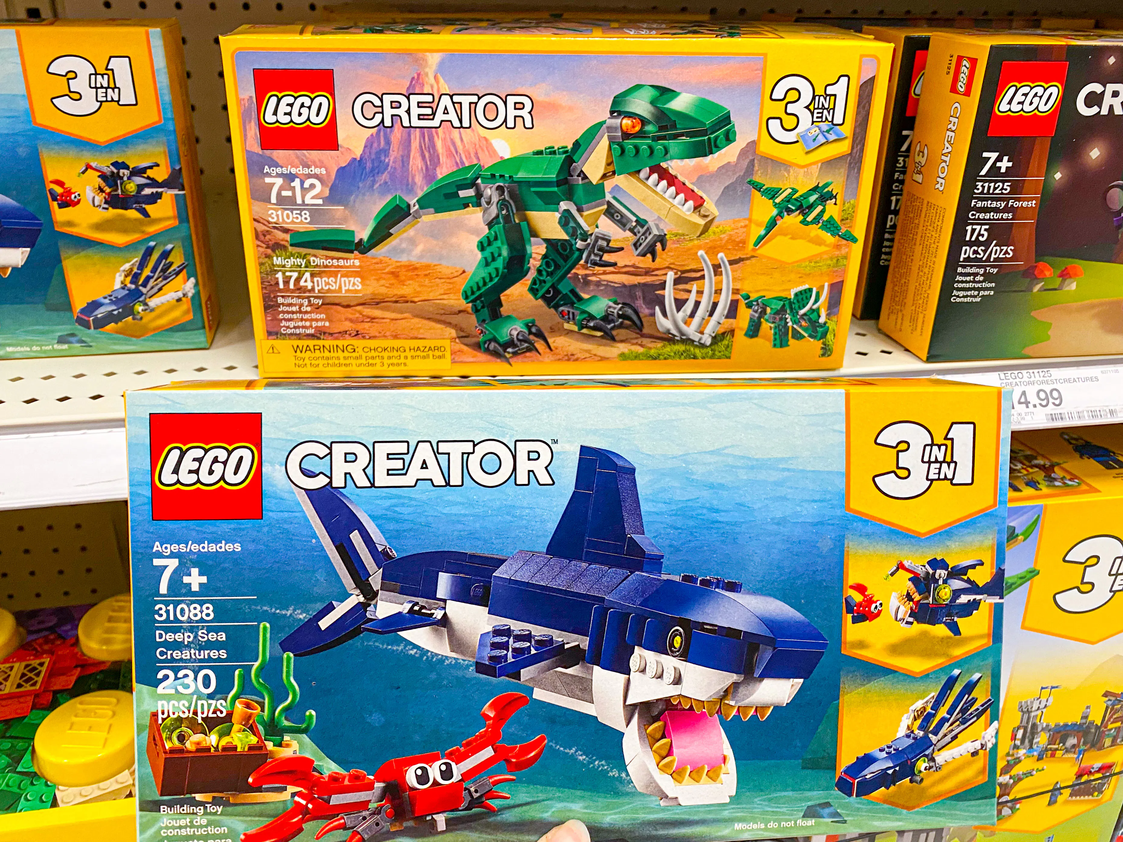 A LEGO Creator 3 in 1 Deep Sea Creatures box set being held in front of more LEGO Creator box sets sitting on a shelf in the LEGO toy aisle at Target.