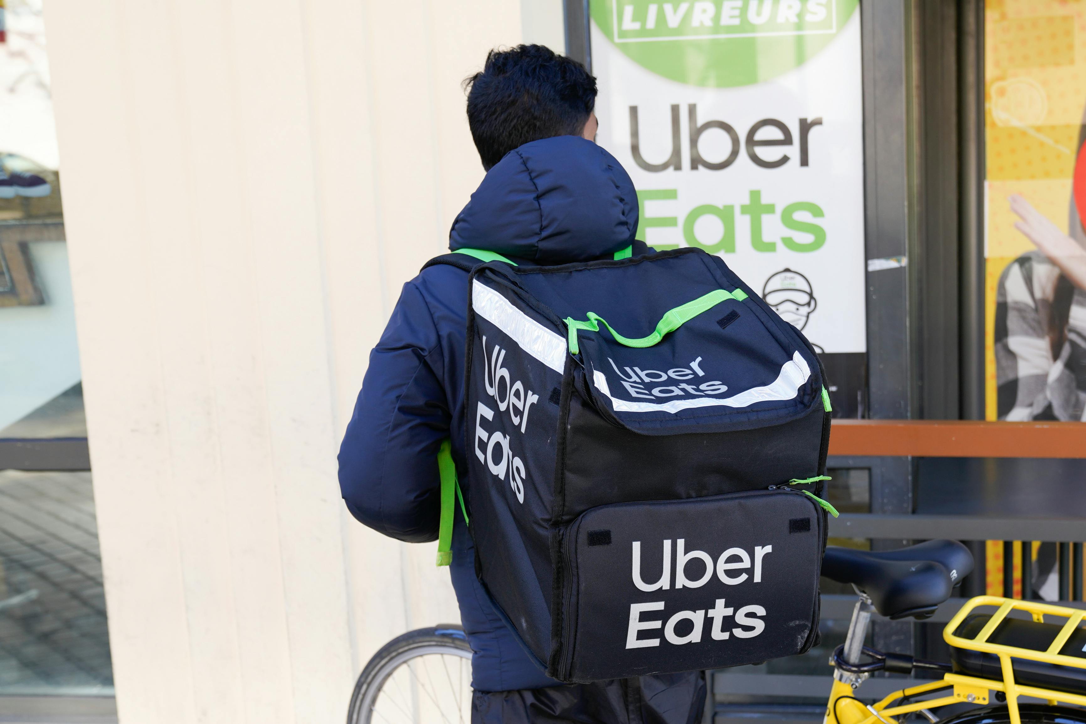 uber eats delivery person wearing backpack near bike