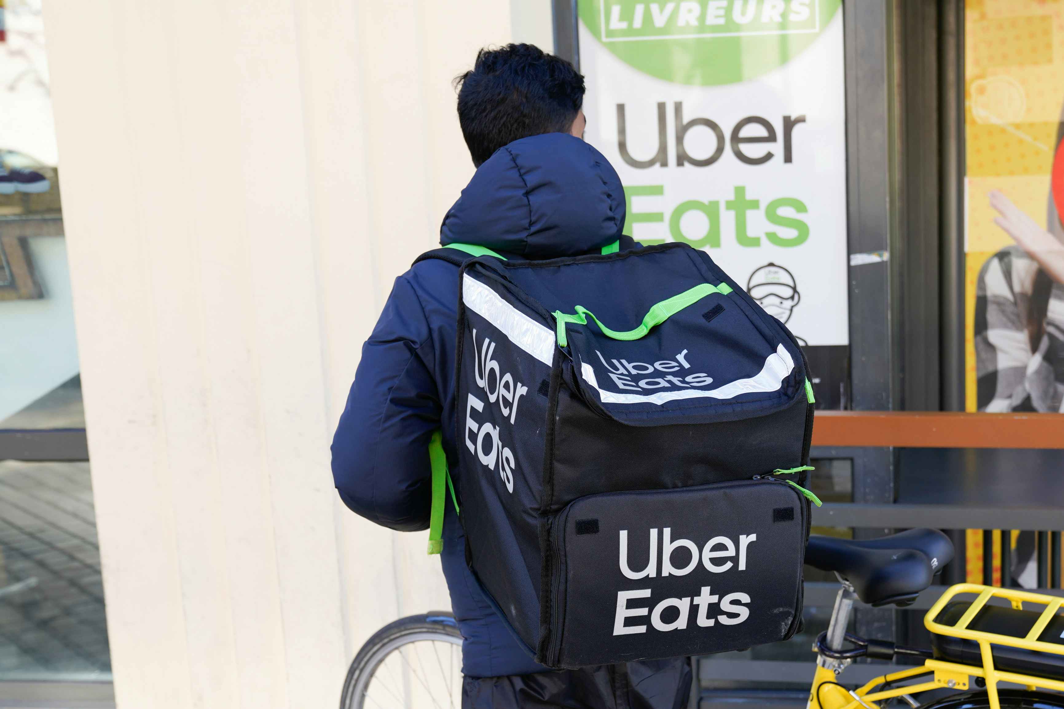 an uber eats delivery man on a bike with an uber eats backpack