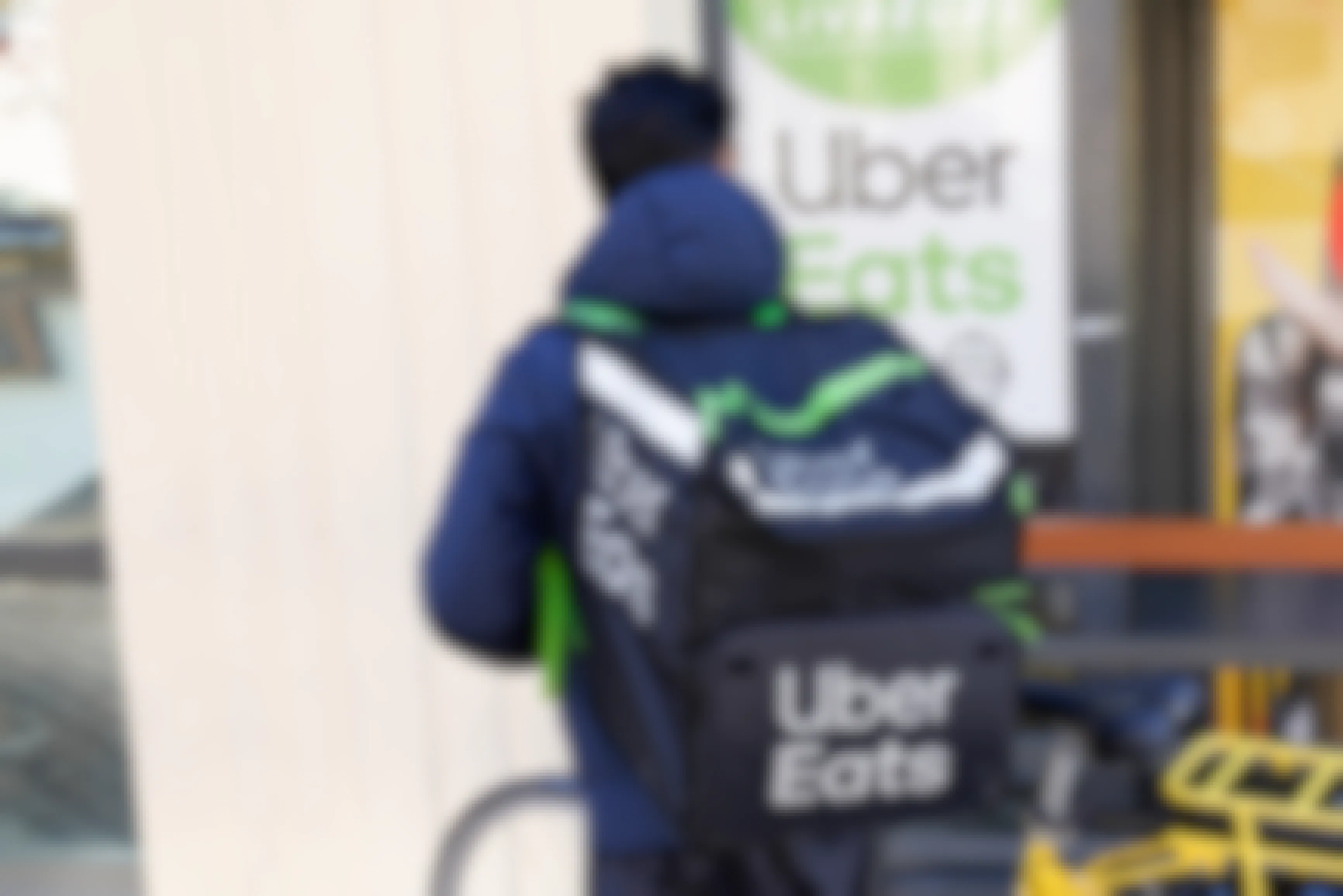 an uber eats delivery man on a bike with an uber eats backpack