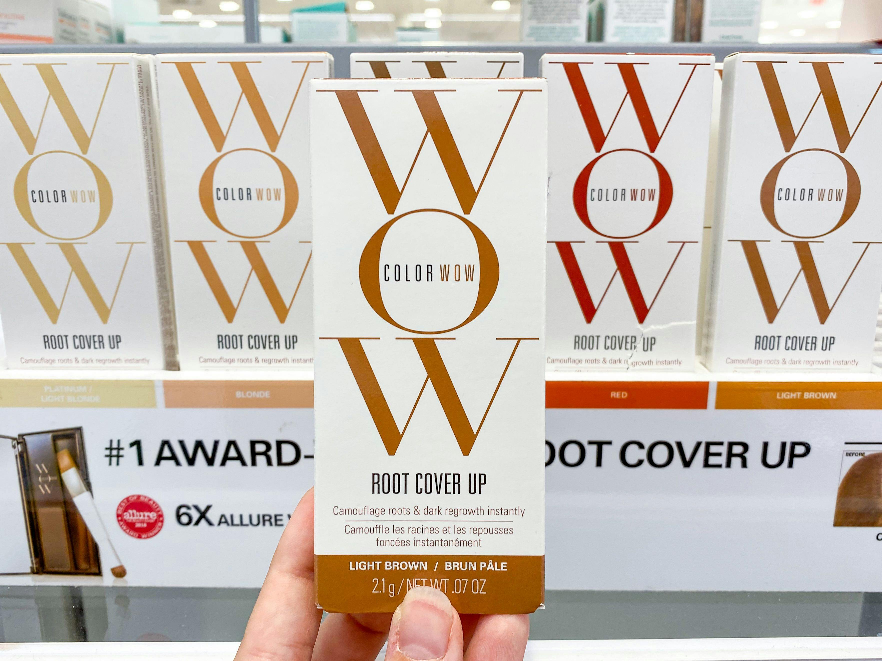 A person holding up a box of ColorWOW root cover up in front of a shelf of other shades in Ulta.