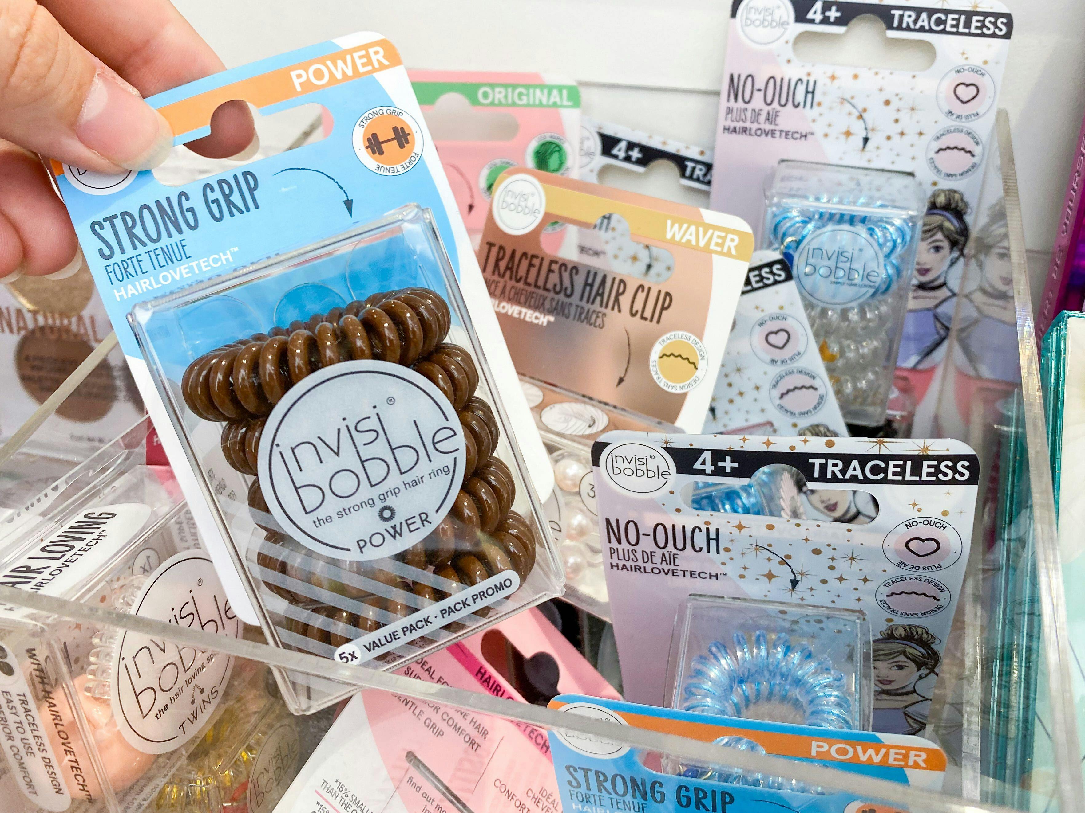 A person picking up a package of invisibobble hair ties inside Ulta.