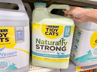 Someone taking a container of Tidy Cats litter from a shelf at Walmart