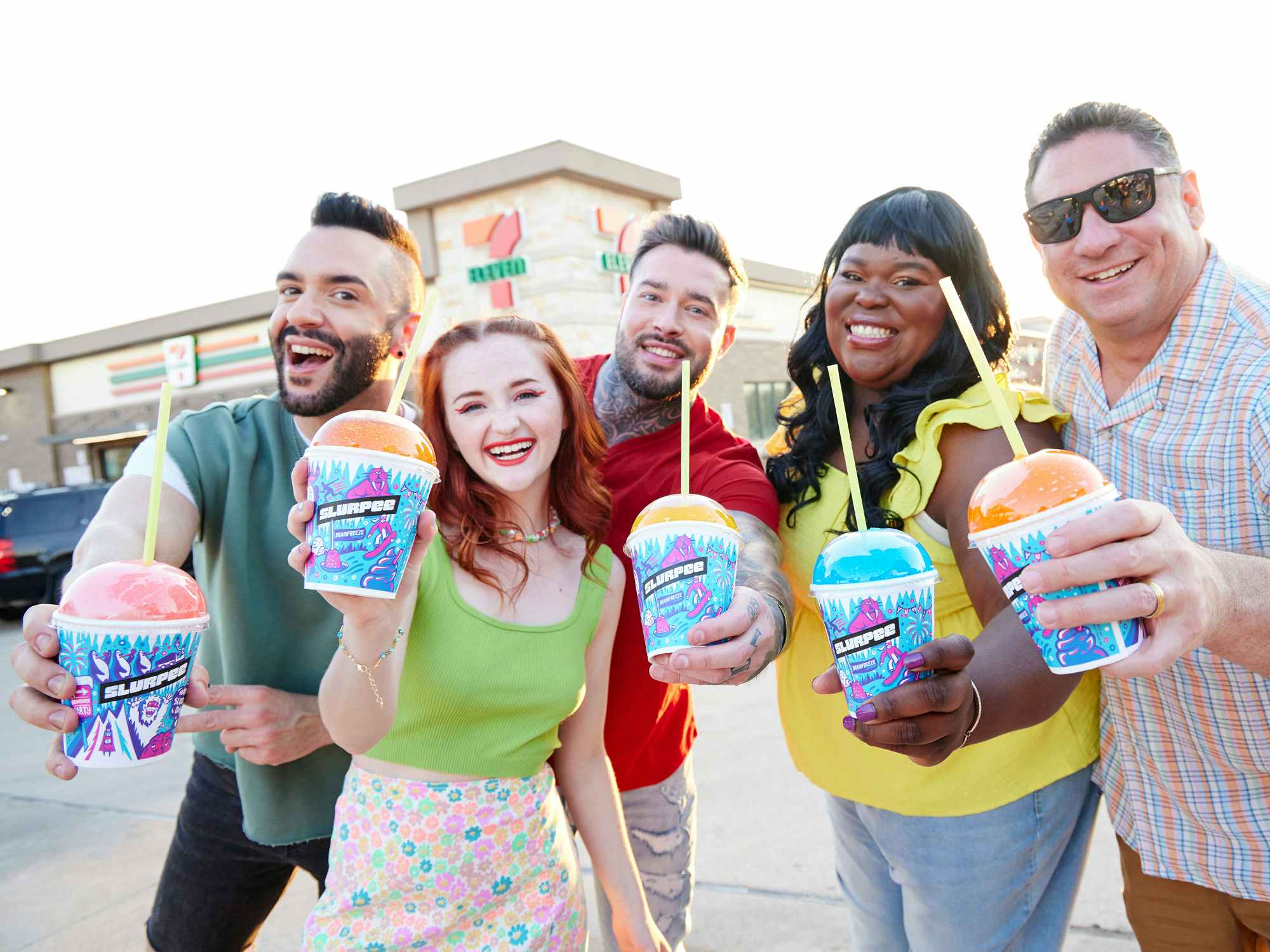 group of happy adults holding slurpees outside 7-eleven