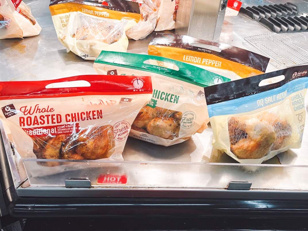 Packages of different flavored rotisserie chickens sitting on a hot shelf inside Albertson's.