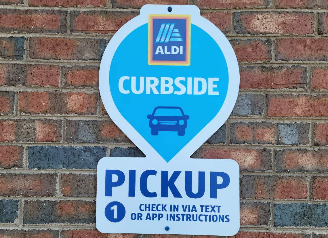 aldi curbside pickup sign on a brick wall