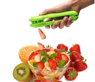 Someone cutting up fruit with a cutter over a bowl of fruit