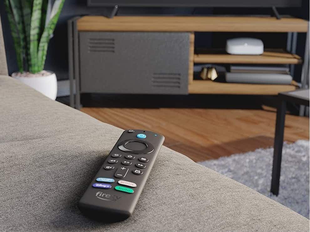 amazon fire tv remote on couch pointing toward tv