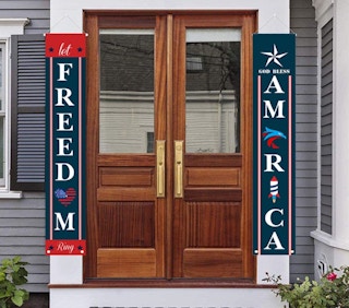 Two ourth of july banners hanging in front of a house's front door