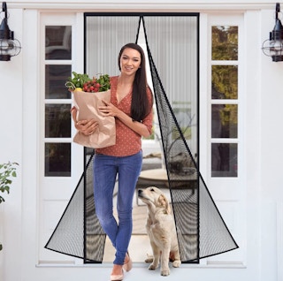 A women going through a screen door with groceries