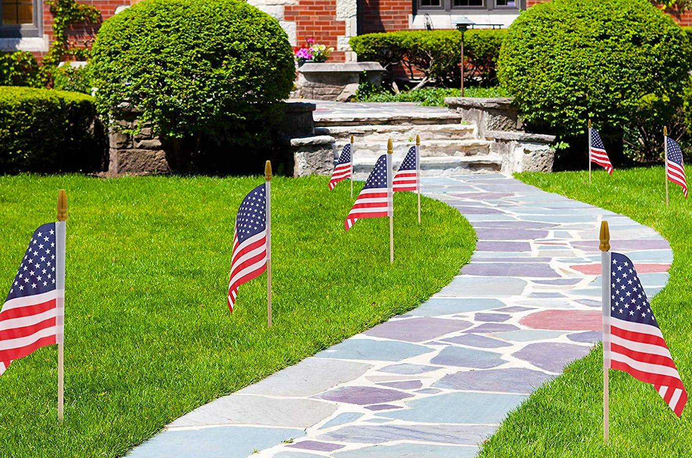 Mini American flags stuck in the ground along a stone path.