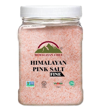 A jar of pink himalayan salt on white background